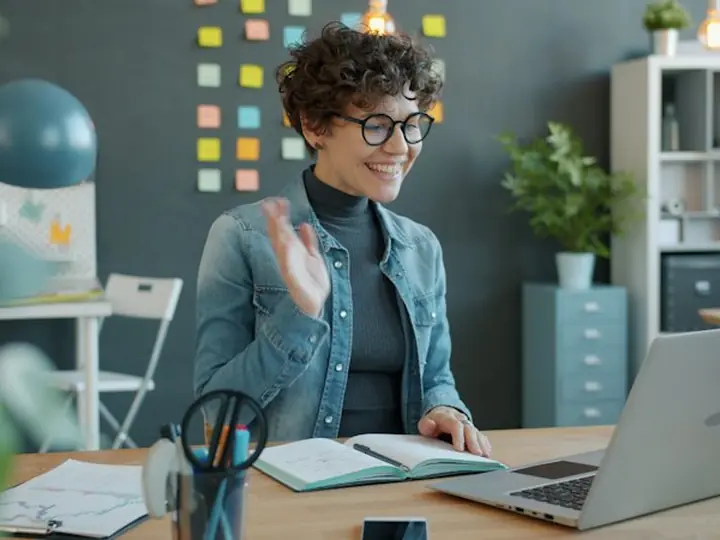 A woman waving hello at the start of a video interview