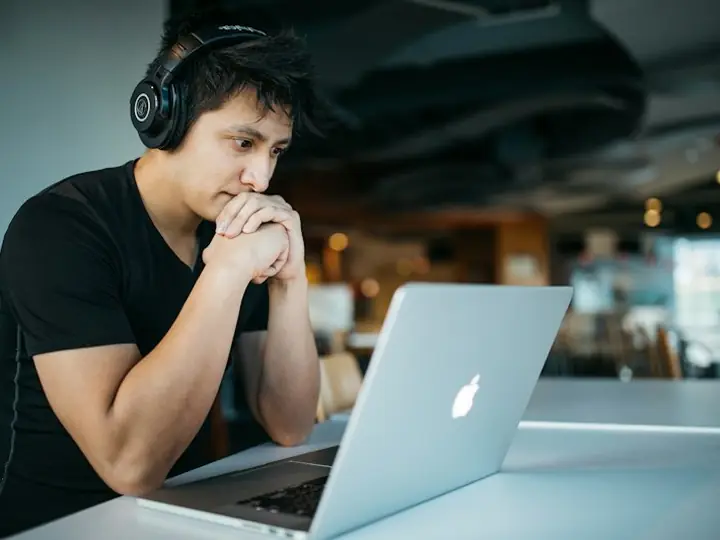 A support agent in headphones on a call at his laptop