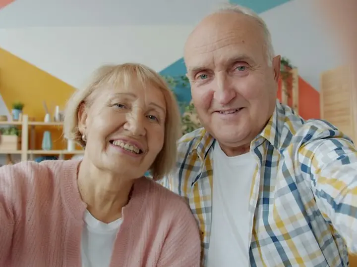 An older couple waving on a video call